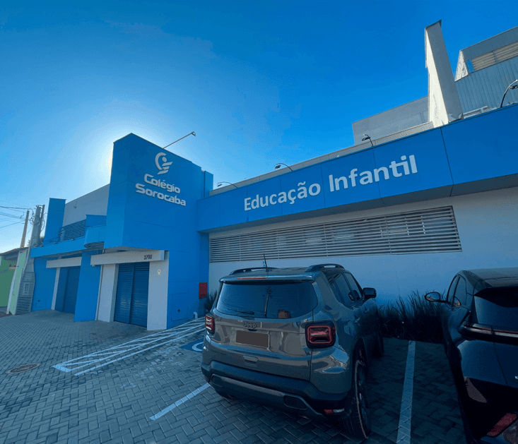 Fachada do Colégio Sorocaba – Educação Infantil, com prédio azul, logotipo da escola e estacionamento em frente, sob céu azul e ensolarado.
